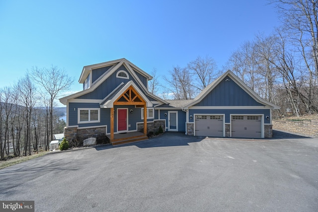 view of front facade with a garage, stone siding, board and batten siding, and driveway