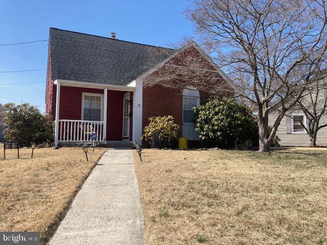 bungalow featuring a porch, a front lawn, and roof with shingles