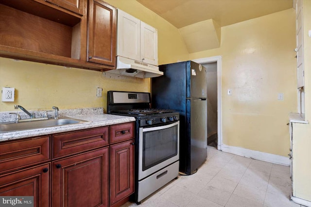 kitchen featuring stainless steel gas stove, under cabinet range hood, a sink, reddish brown cabinets, and light countertops