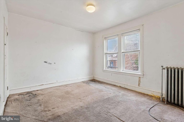 unfurnished room with radiator heating unit and carpet floors