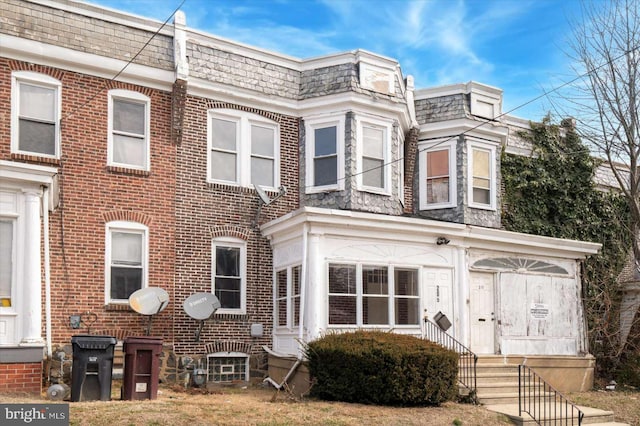 townhome / multi-family property with entry steps, mansard roof, and brick siding