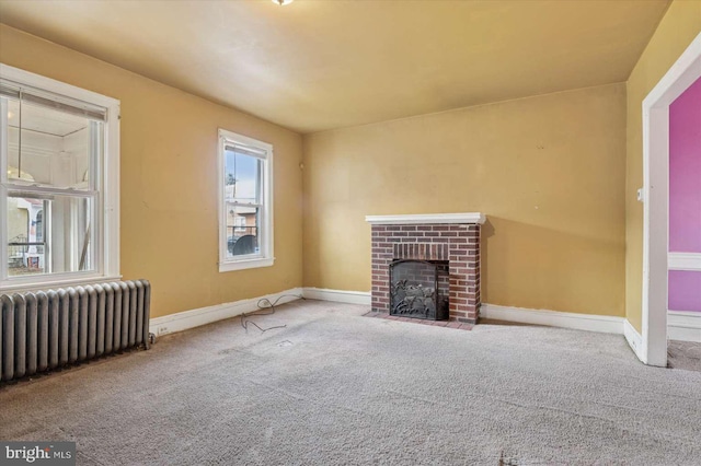 unfurnished living room with baseboards, carpet, a brick fireplace, and radiator heating unit