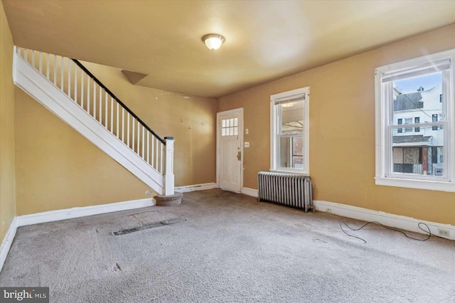 entrance foyer with stairs, radiator, a wealth of natural light, and carpet floors