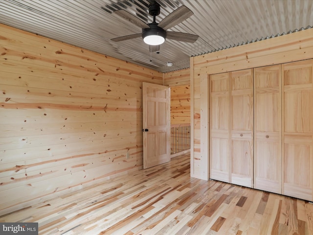 120 Honeymoon Hollow Rd, Lost City, WV 26810 - unfurnished bedroom with a ceiling fan, wood walls, light wood-style flooring, and a closet