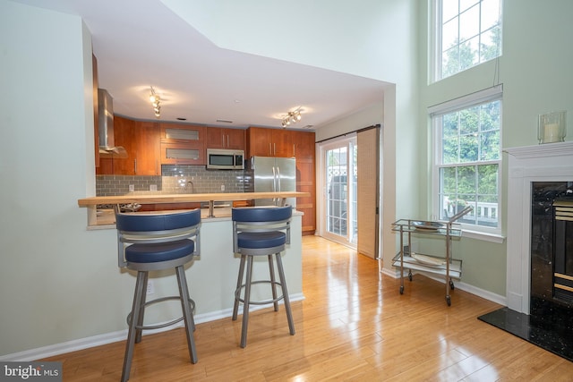215 Valley Frg, Lookout Place, Wayne, PA 19087 - kitchen with stainless steel appliances, brown cabinets, a peninsula, a high end fireplace, and glass insert cabinets