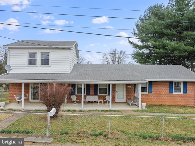 traditional-style home with a fenced front yard, brick siding, covered porch, and a front yard