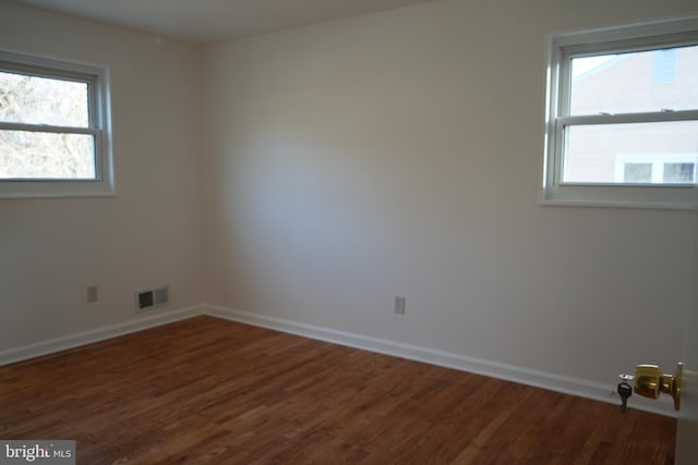 spare room with visible vents, dark wood-type flooring, and baseboards