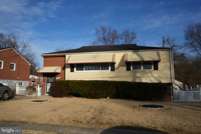 view of front of house featuring brick siding and fence