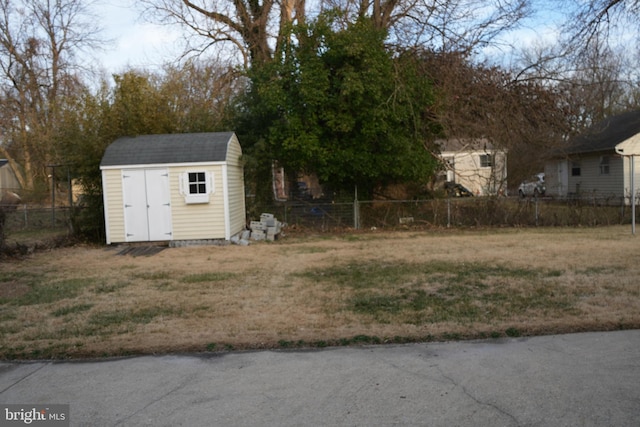 view of yard featuring an outbuilding, a storage unit, and fence