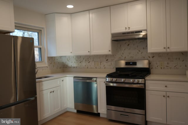 kitchen with white cabinets, under cabinet range hood, and stainless steel appliances