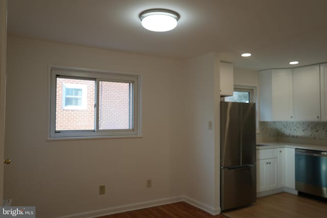 kitchen featuring white cabinets, appliances with stainless steel finishes, light countertops, and wood finished floors