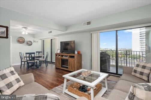 living room with visible vents, baseboards, a ceiling fan, and wood finished floors