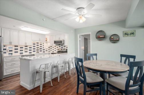 dining area with dark wood-style flooring and ceiling fan