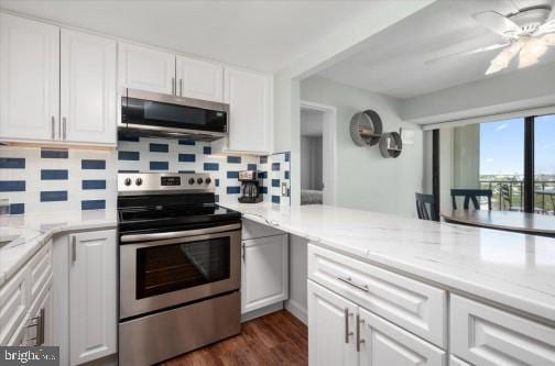 kitchen featuring light stone countertops, dark wood finished floors, stainless steel appliances, decorative backsplash, and white cabinets