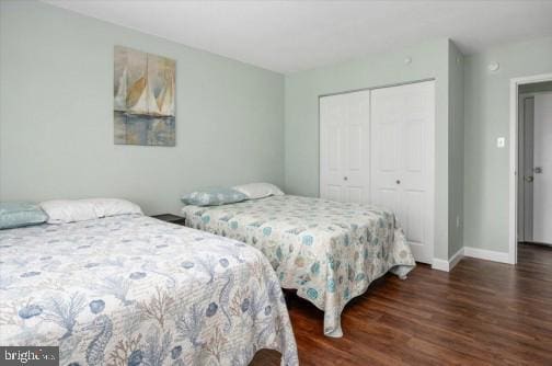 bedroom with wood finished floors, a closet, and baseboards