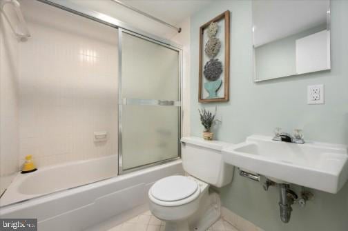 bathroom with toilet and bath / shower combo with glass door