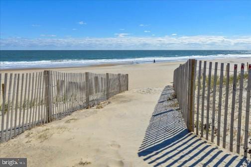 property view of water featuring a beach view and fence