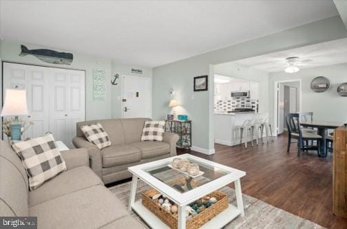 living area with wood finished floors, baseboards, and ceiling fan