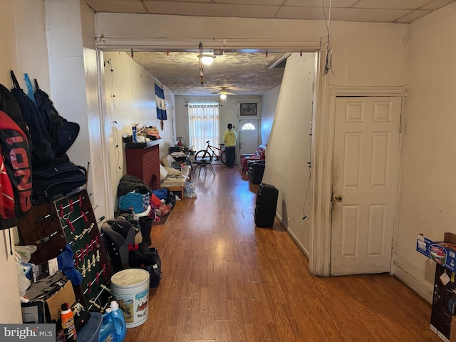 hall with wood finished floors, baseboards, and a drop ceiling