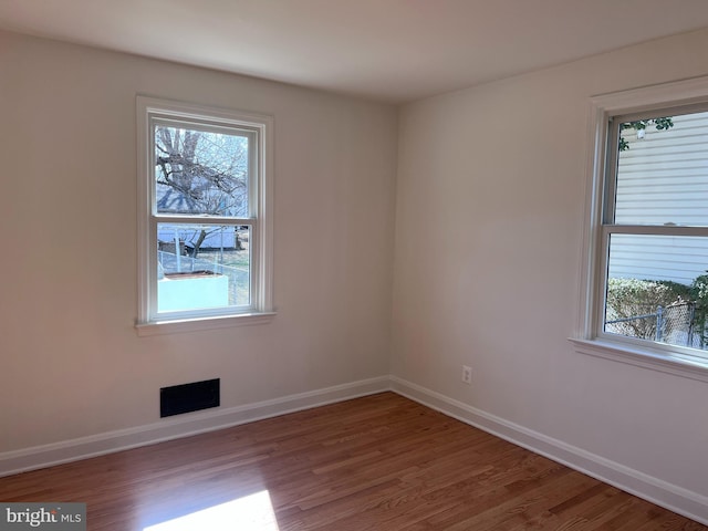 spare room featuring visible vents, baseboards, and wood finished floors