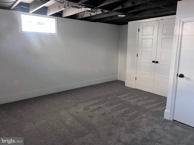 below grade area featuring baseboards and dark colored carpet