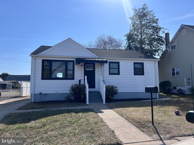 bungalow with roof with shingles, a front lawn, and fence