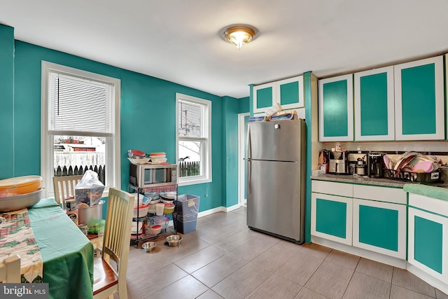 kitchen with dark countertops, freestanding refrigerator, and baseboards