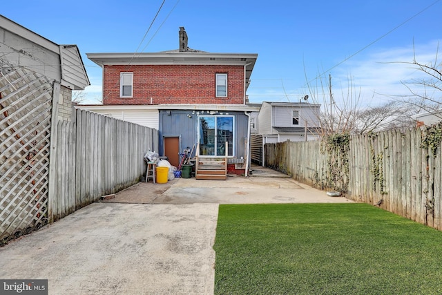 back of house with a patio, a yard, a fenced backyard, entry steps, and brick siding