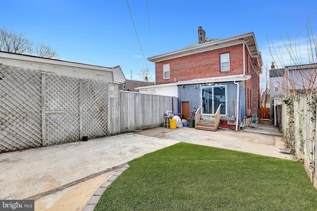 back of house featuring brick siding, a fenced backyard, entry steps, a patio area, and a lawn