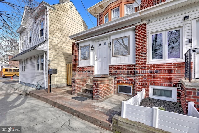 doorway to property featuring brick siding and fence