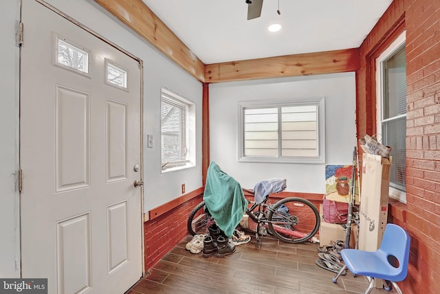 foyer entrance with brick wall and wood finished floors