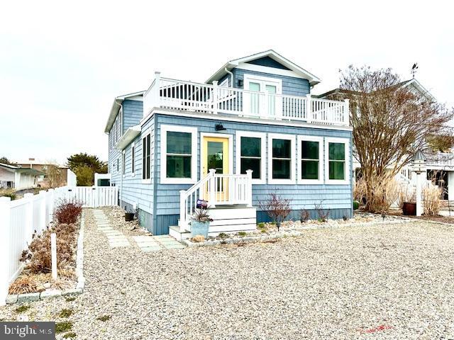 1 E Essex St, Fenwick Island, DE 19944 - view of front of house featuring a balcony and fence
