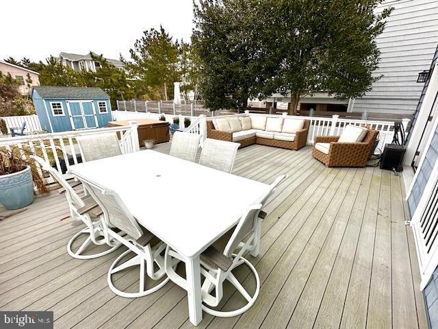 1 E Essex St, Fenwick Island, DE 19944 - wooden terrace with a shed, an outdoor living space, an outbuilding, outdoor dining space, and a fenced backyard