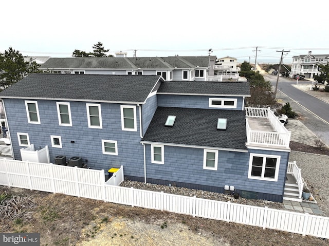 1 E Essex St, Fenwick Island, DE 19944 - back of property featuring fence, cooling unit, and roof with shingles