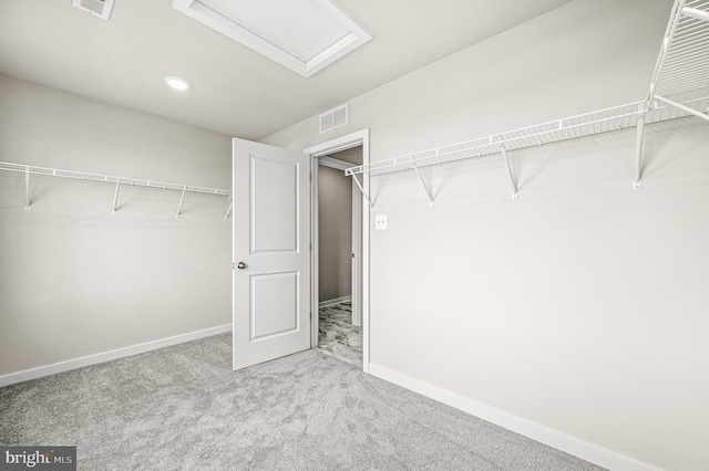 spacious closet featuring visible vents, carpet floors, and attic access