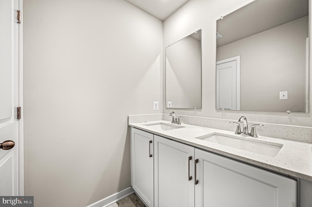 bathroom with a sink, baseboards, and double vanity