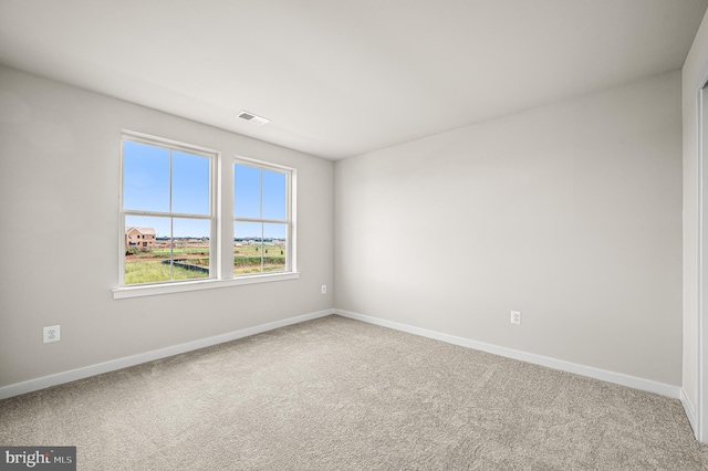 carpeted empty room featuring visible vents and baseboards