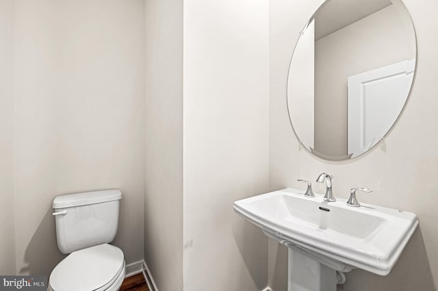 bathroom with toilet, baseboards, and a sink