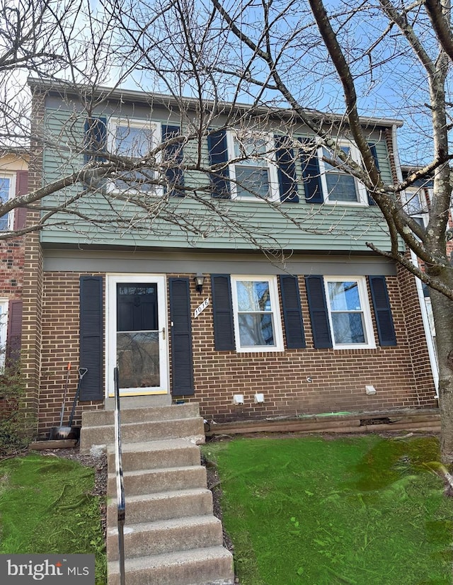 view of front of home with entry steps, a front yard, and brick siding