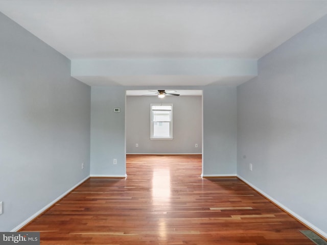 spare room with wood finished floors, baseboards, a ceiling fan, and visible vents