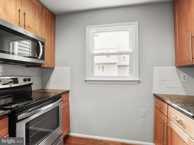 kitchen with tasteful backsplash, baseboards, appliances with stainless steel finishes, and brown cabinets