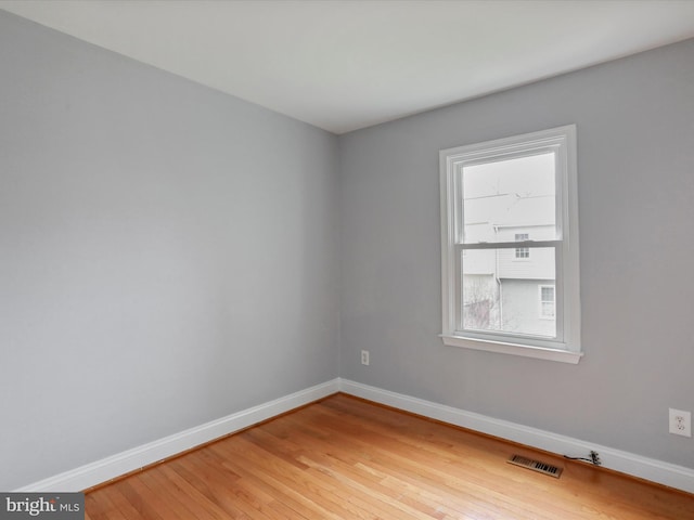 spare room with a healthy amount of sunlight, light wood finished floors, baseboards, and visible vents