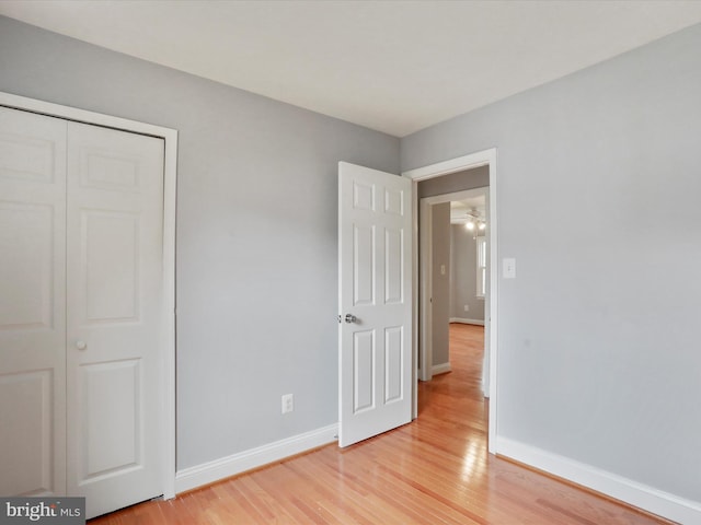 unfurnished bedroom with a closet, light wood-type flooring, and baseboards