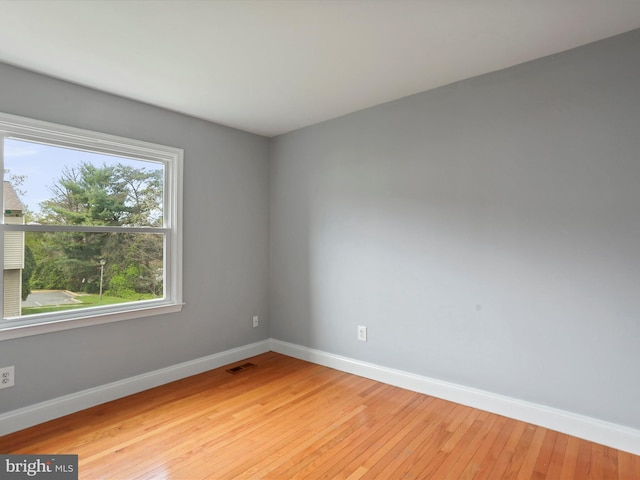 unfurnished room featuring light wood-type flooring, visible vents, and baseboards