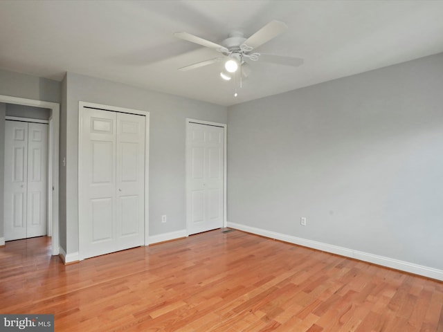 unfurnished bedroom featuring light wood-style floors, baseboards, and multiple closets