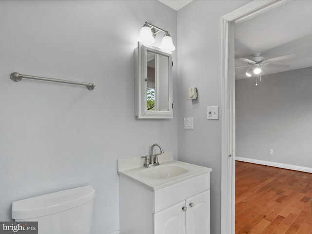 bathroom featuring vanity, baseboards, toilet, ceiling fan, and wood finished floors