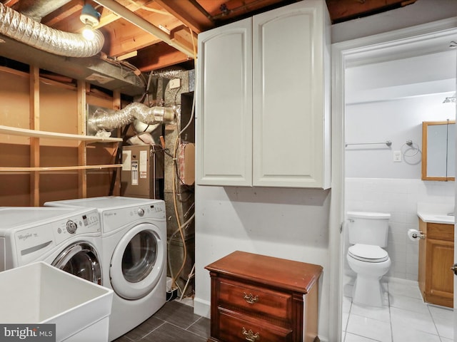 laundry area featuring tile patterned flooring, tile walls, and separate washer and dryer