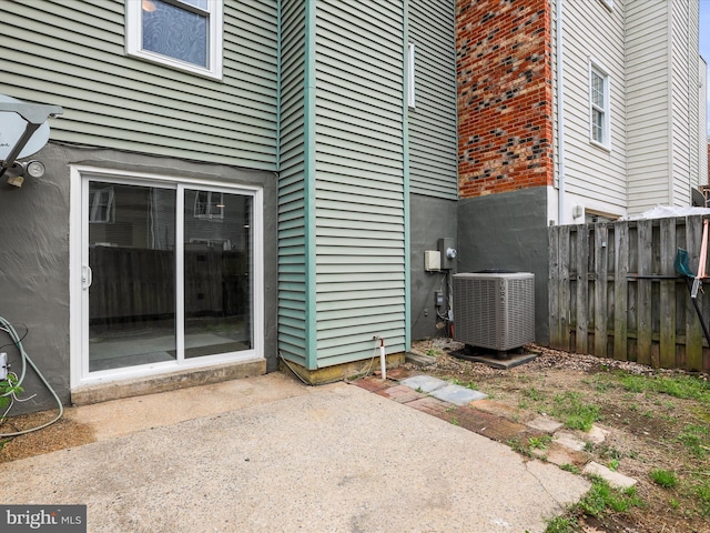 property entrance with a patio, cooling unit, and fence