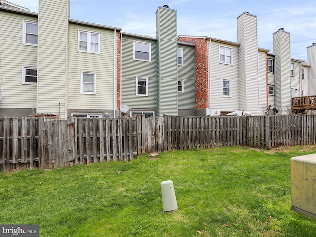 back of house featuring a fenced backyard and a lawn