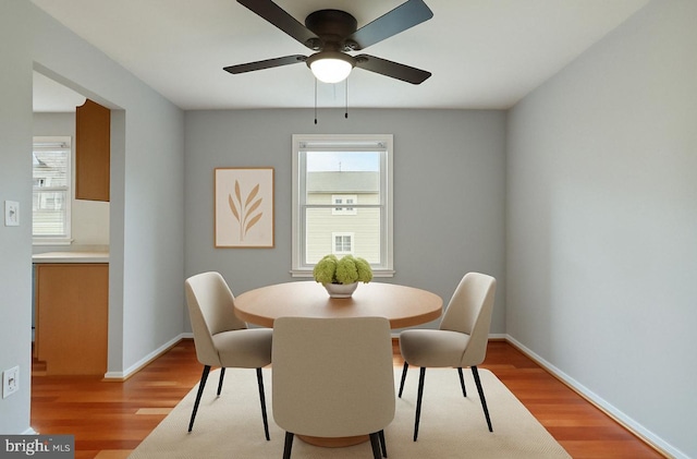 dining area with light wood-style flooring, baseboards, and a ceiling fan